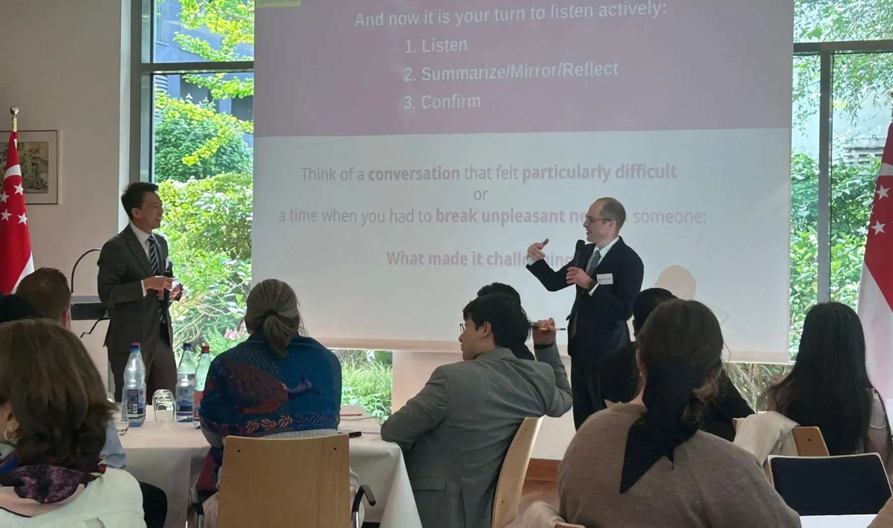 Workshop zu Aktivem Zuhören in der Botschaft von Singapur, zwei Vortragende vor einer Folie