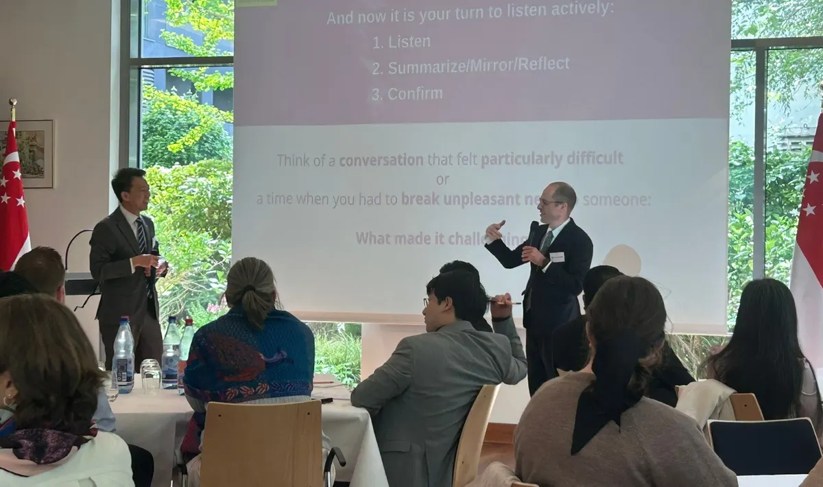 Workshop zu Aktivem Zuhören in der Botschaft von Singapur, zwei Vortragende vor einer Folie