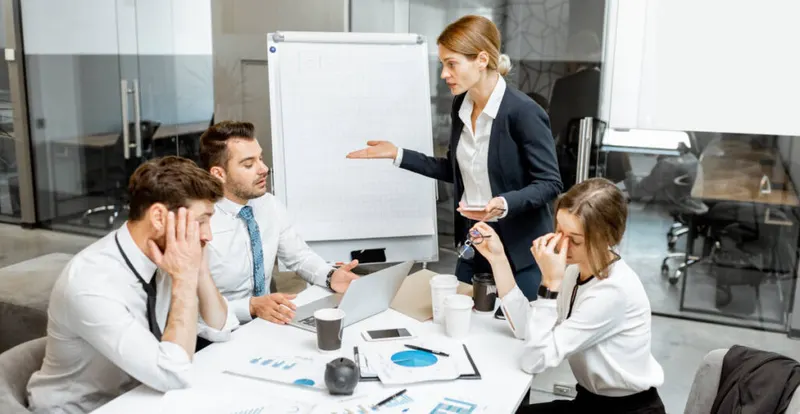 Angespannte Besprechung mit vier Personen vor einem Flipchart